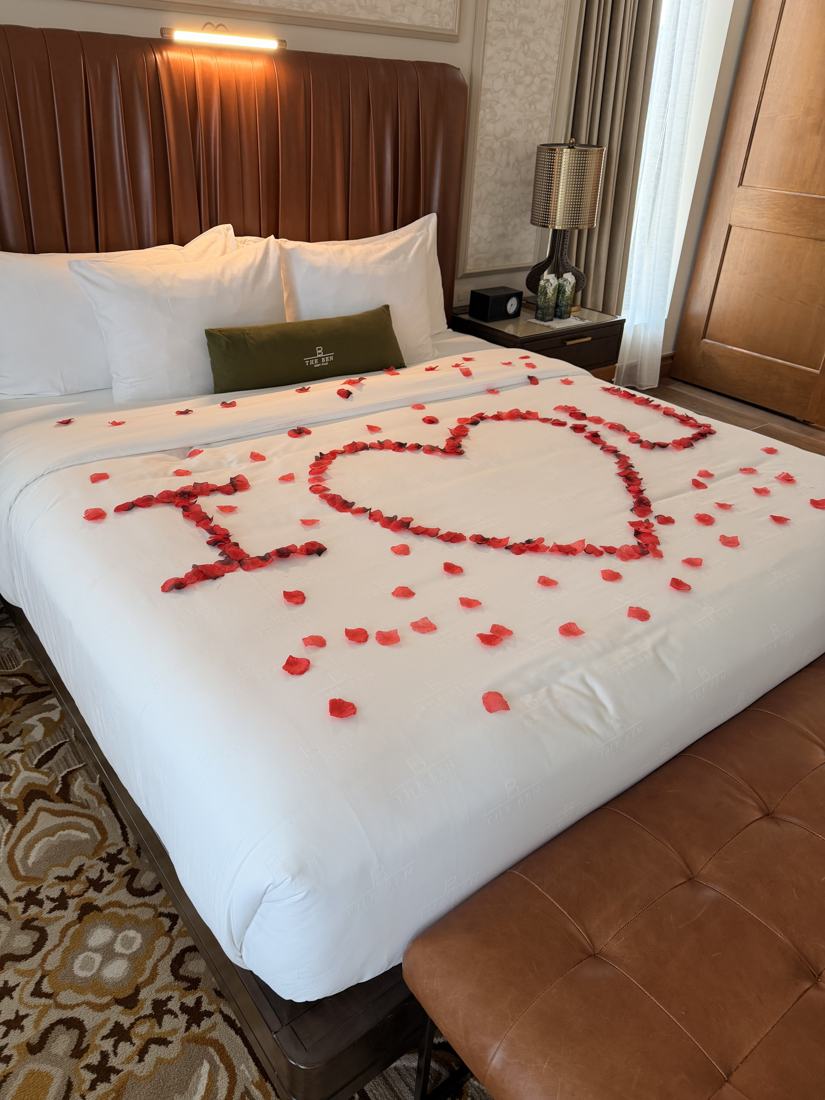 Rose petals spelling I love U on a hotel bed